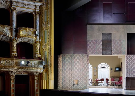 Linkes Proszenium mit linkem Teil der Bühnenarchitektur und Durchblick in eine der beiden Barräume. Das Mobiliar wurde wiederverwendet aus einer Produktion von Luisa Miller an der Oper Frankfurt 1996.