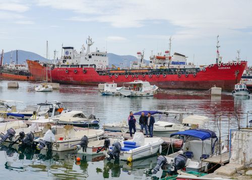 Kleine Fischerboote liegen neben grossen Containerschiffen im Hafen von Piräus